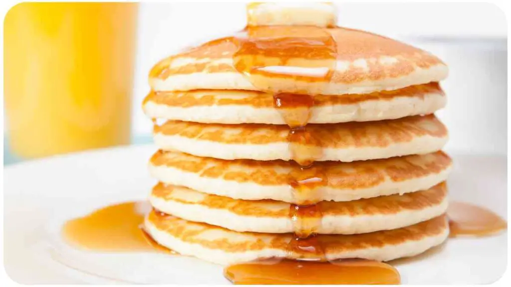 a stack of pancakes on a white plate with syrup
